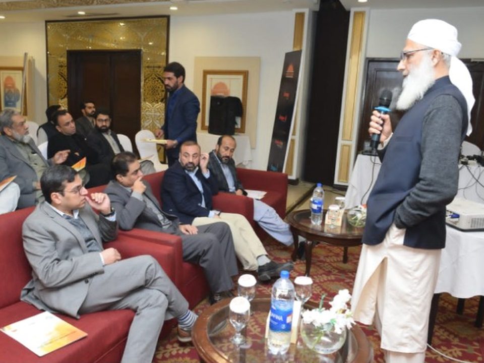 A senior speaker with a microphone talking with doctors seated on red sofas